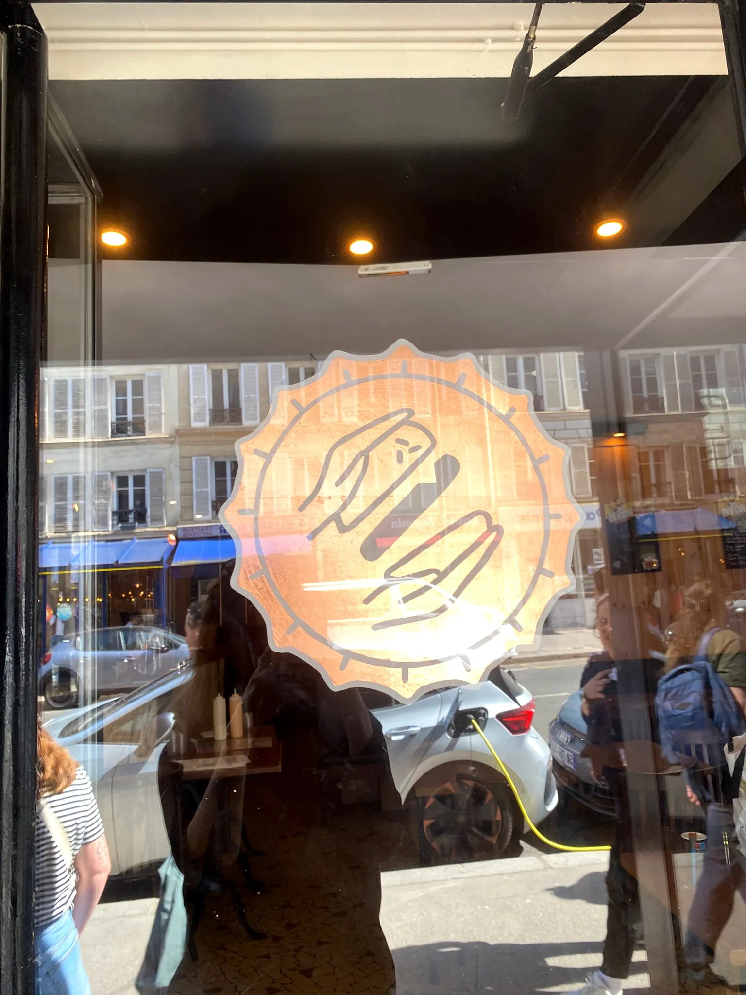 Logo de La Clap peint sur une vitre — deux mains dans une capsule dentelée, à la feuille de cuivre