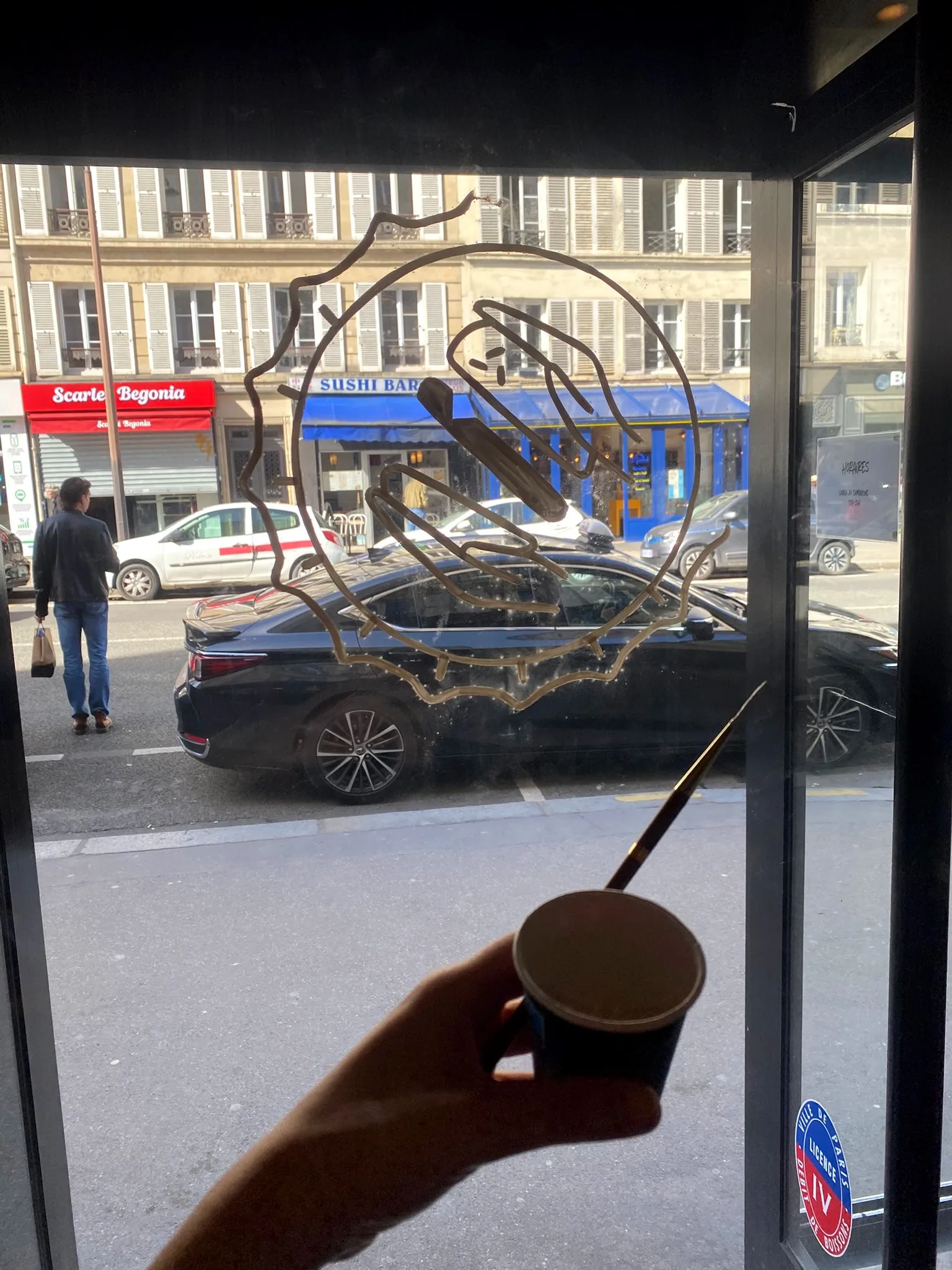 Le tracé du logo de La Clap peint à l’envers sur la vitre, en cours