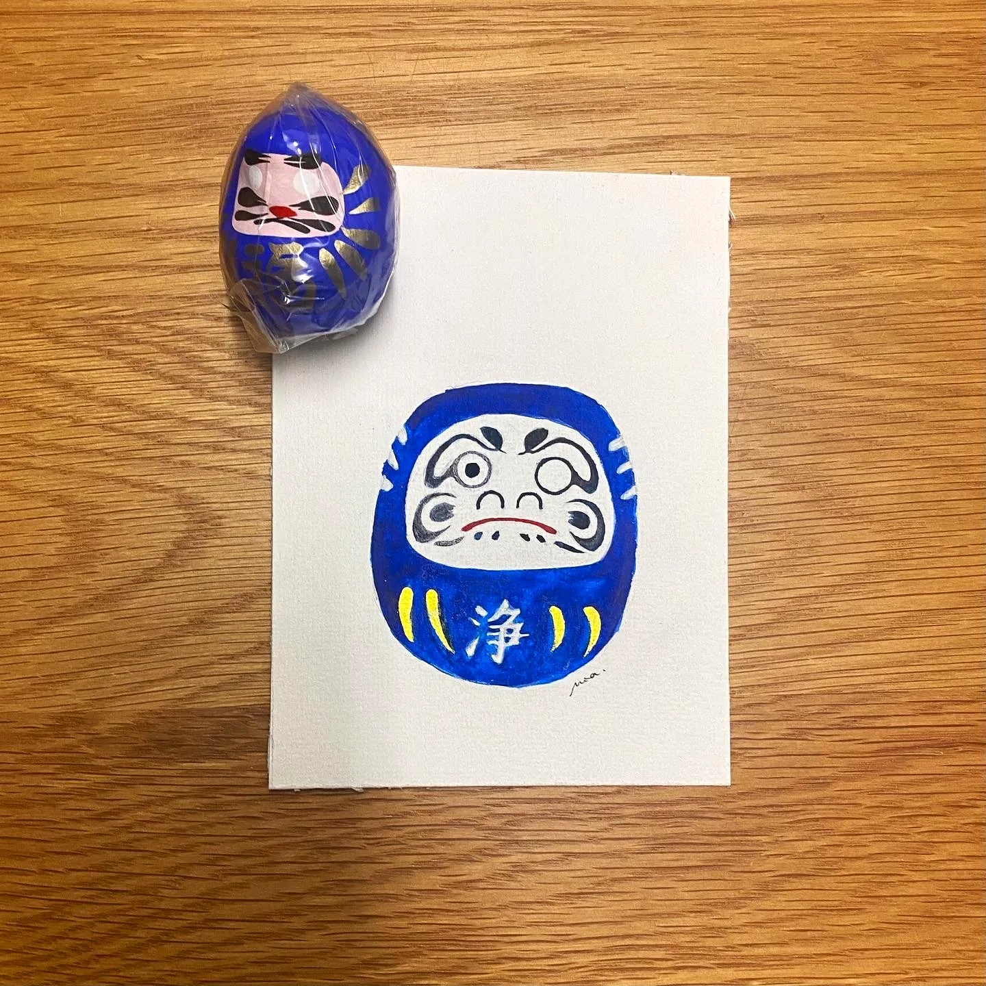 L'aquarelle du daruma à côté du modèle réel