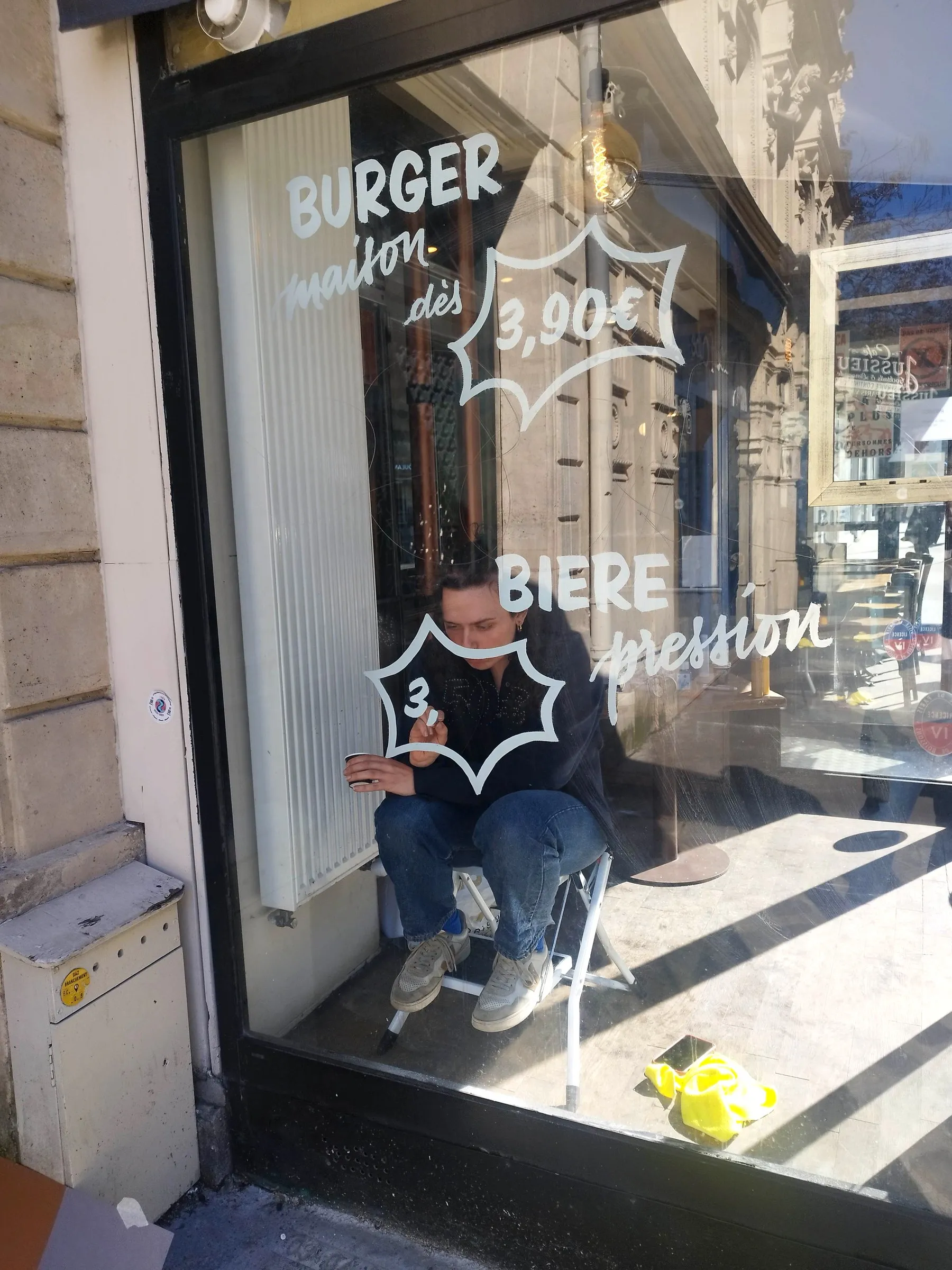 Assise sur un petit escabeau, à peindre une bulle de prix