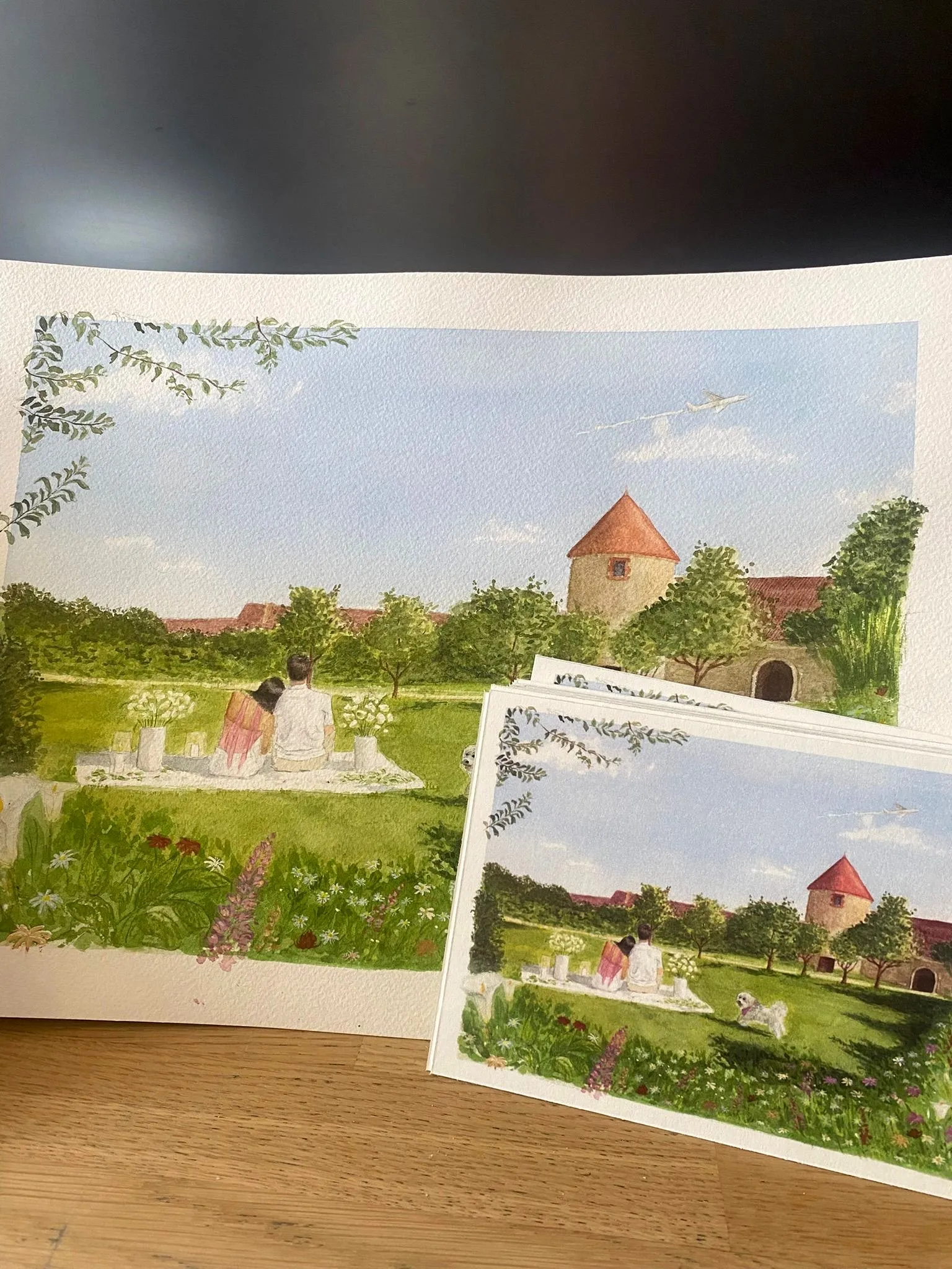 L’aquarelle finie et la pile de faire-part imprimés